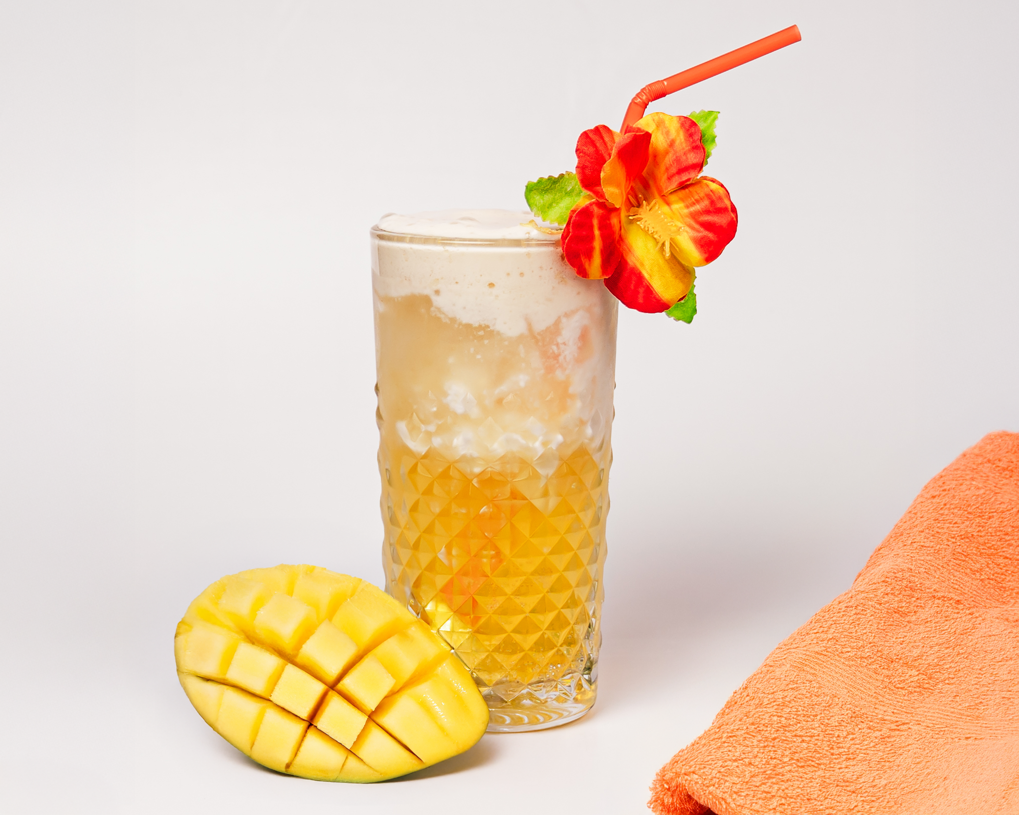 Tropical fizzy drink with mango and pineapple elements in a tall glass.